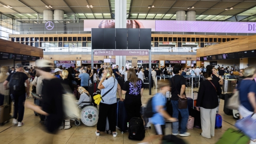 Numerous passengers wait in front of a black display board at the capital's Berlin Brandenburg Airport, in Schönefeld, Germany, Friday July 19, 2024. Air traffic has been suspended at BER Airport. A widespread Microsoft outage was disrupting flights, banks, media outlets and companies around the world on Friday. (Christoph Soeder/dpa via AP)