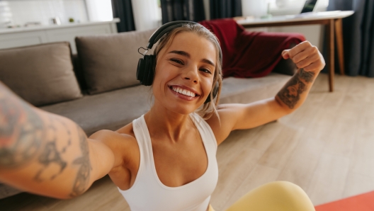 Top view of happy sporty woman making selfie while resting on exercise mat after home workout