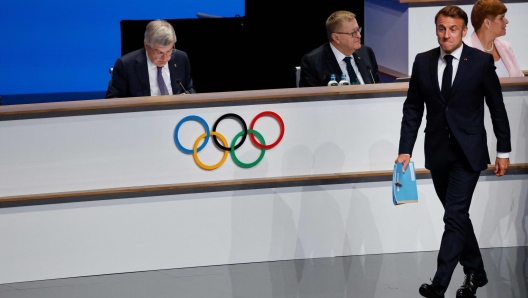 TOPSHOT - French President Emmanuel Macron (R) walks past International Olympic Committe (IOC) President Thomas Bach during the French Alps' bid for the 2030 Winter Games during the 142nd session of the IOC in Paris on July 24, 2024, ahead of the Paris 2024 Olympic Games. (Photo by Ludovic MARIN / AFP)