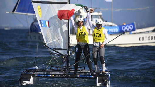 Italy's Ruggero Tita (L) and Caterina Banti celebrate winning the gold medal after the mixed multihull Nacra 17 foiling race during the Tokyo 2020 Olympic Games sailing competition at the Enoshima Yacht Harbour in Fujisawa, Kanagawa Prefecture on August 3, 2021. (Photo by Olivier MORIN / AFP)