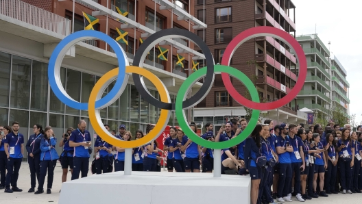 French athletes gather near Olympic rings as he visits the Olympic Village, at the 2024 Summer Olympics, Monday, July 22, 2024, in Paris, France. (AP Photo/Michel Euler, Pool)