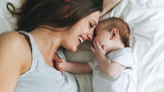 Young mother having fun with cute baby girl on bed, natural tones, love emotion