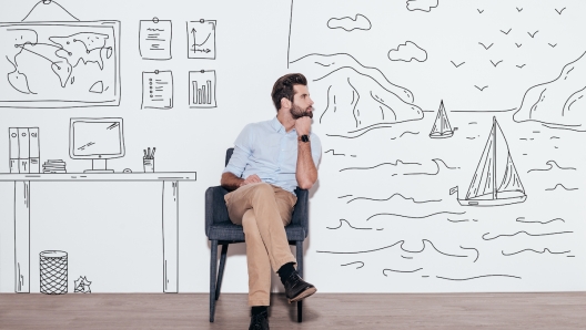 Young handsome man keeping hand on chin and looking away while sitting in the chair against illustration of fjord vs. working place