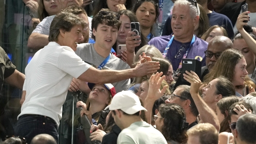 Actor Tom Cruise, left, interacts with fans as he attends the women's artistic gymnastics qualification round at the 2024 Summer Olympics, Sunday, July 28, 2024, in Paris, France. (AP Photo/Charlie Riedel)