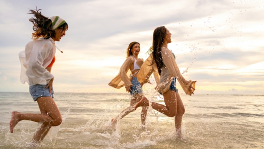 Group of Young Asian woman enjoy and fun outdoor lifestyle travel nature ocean on summer beach holiday vacation. Attractive girl friends walking and playing together at the sea on tropical island.