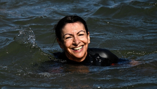 Paris Mayor Anne Hidalgo swims in the Seine, in Paris on July 17, 2024, to demonstrate that the river is clean enough to host the outdoor swimming events at the Paris Olympics later this month. Despite an investment of 1.4 billion euros ($1.5 billion) to prevent sewage leaks into the waterway, the Seine has been causing suspense in the run-up to the opening of the Paris Games on July 26 after repeatedly failing water quality tests. But since the beginning of July, with heavy rains finally giving way to sunnier weather, samples have shown the river to be ready for the open-water swimming and triathlon -- and for 65-year-old Hidalgo. (Photo by JULIEN DE ROSA / AFP)