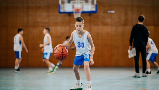 Energetic young player dribbles a basketball on the court, highlighting the dynamic nature of youth sports