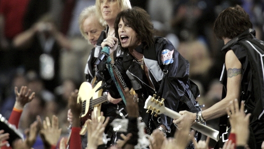 FILE - Aerosmith members, from left, Brad Whitford, Tom Hamilton, Steven Tyler and Joe Perry rock during the opening show for the NFL Super Bowl XXXVIII football game Sunday, Feb. 1, 2004, in Houston. When the Super Bowl halftime show was born, high school and college marching bands took center field. But over the years, the intermission during the NFL?s championship game has turned into one of sports? biggest spectacles with superstar performances.(AP Photo/Michael Conroy, File)