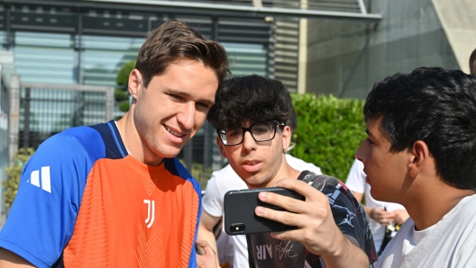 TURIN, ITALY - JULY 23: Federico Chiesa of Juventus FC greets fans and takes photos and signs autographs after he arrives for medical tests and first day back in training on July 23, 2024 in Turin, Italy. (Photo by Chris Ricco - Juventus FC/Juventus FC via Getty Images)