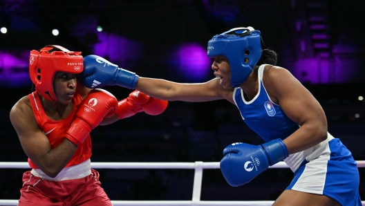 Refugee Olympic Team's Cindy Winner Djankeu Ngamba and France's Davina Michel (Blue) compete in the women's 75kg quarter-final boxing match during the Paris 2024 Olympic Games at the North Paris Arena, in Villepinte on August 4, 2024. (Photo by MOHD RASFAN / AFP)