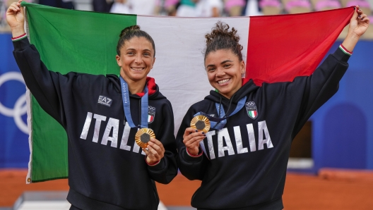 Sara Errani, left, and Jasmine Paolini of Italy show their gold medals after defeating Mirra Andreeva and Diana Shnaider of Individual Neutral Athlete during women's doubles gold medal tennis match at the Roland Garros stadium, at the 2024 Summer Olympics, Sunday, Aug. 4, 2024, in Paris, France. (AP Photo/Manu Fernandez)