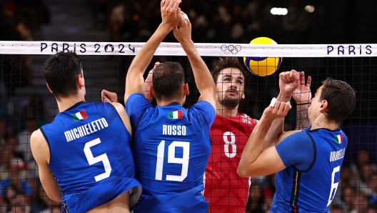 PARIS, FRANCE - AUGUST 09: Torey Defalco #8 of Team United States attacks the net against Alessandro Michieletto #5, Roberto Russo #19 and Simone Giannelli #6 of Team Italy during a Men's Bronze Medal Match between Team Italy and Team United States on day fourteen of the Olympic Games Paris 2024 at Paris Arena on August 09, 2024 in Paris, France. (Photo by Buda Mendes/Getty Images)