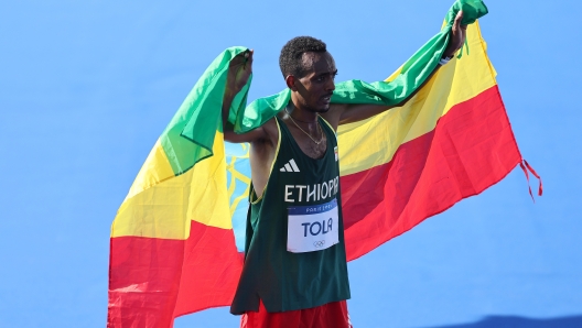 PARIS, FRANCE - AUGUST 10: Gold medalist Tamirat Tola of Team Ethiopia reacts following the Men's Marathon on day fifteen of the Olympic Games Paris 2024 at Esplanade Des Invalides on August 10, 2024 in Paris, France. (Photo by Hannah Peters/Getty Images)