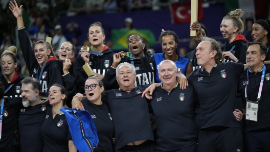 Italy's coach Julio Velasco, front row center, celebrate the gold medal with the team during the medal ceremony after the women's volleyball match against the United States at the 2024 Summer Olympics, Sunday, Aug. 11, 2024, in Paris, France. (AP Photo/Alessandra Tarantino)