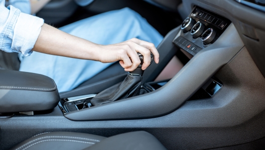 Woman switching gear, holding handle of the automatic gearbox of the modern car, close-up view