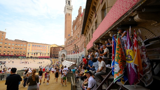 SIENA, ITALY - AUGUST 16: Fans and tourists take place in Piazza del Campo ahead the main event at the Palio di Siena on August 16, 2024 in Siena, Italy. The historic horse race, ridden by jockeys on bareback, is held twice each year on 2 July and 16 August in Siena and consists of three laps of the Piazza del Campo. (Photo by Rudy Carezzevoli/Getty Images)