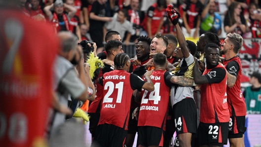 Bayer Leverkusen's players celebrate with Finnish goalkeeper #01 Lukas Hradecky after winning the penalty shoot-out of the German Supercup football match between Bayer 04 Leverkusen and VfB Stuttgart in Leverkusen, western Germany on August 17, 2024. (Photo by Sascha Schuermann / AFP) / DFL REGULATIONS PROHIBIT ANY USE OF PHOTOGRAPHS AS IMAGE SEQUENCES AND/OR QUASI-VIDEO