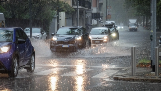 Persone si riparano dalla pioggia con un ombrello durante un temporale a Milano, 5 settembre 2024. ANSA/MATTEO CORNER