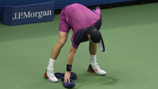 Jack Draper, of Great Britain, wipes the court against Jannik Sinner, of Italy, during the men's singles semifinals of the U.S. Open tennis championships, Friday, Sept. 6, 2024, in New York. (AP Photo/Seth Wenig)