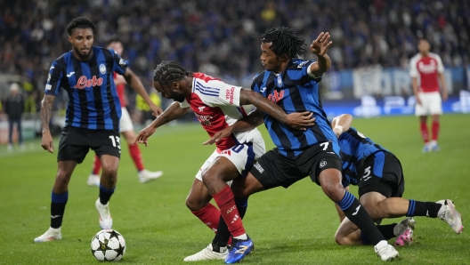 Arsenal's Raheem Sterling, centre left, and Atalanta's Juan Cuadrado challenge for the ball during the Champions League opening phase soccer match between Atalanta and Arsenal at the Bergamo's stadium in Bergamo, Italy, Thursday, Sept. 19, 2024. (AP Photo/Antonio Calanni)