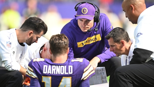 MINNEAPOLIS, MINNESOTA - SEPTEMBER 22: Kevin O'Connell, head coach of the Minnesota Vikings, checks on quarterback Sam Darnold #14 after an apparent injury during the third quarter against the Houston Texans at U.S. Bank Stadium on September 22, 2024 in Minneapolis, Minnesota.   Stephen Maturen/Getty Images/AFP (Photo by Stephen Maturen / GETTY IMAGES NORTH AMERICA / Getty Images via AFP)