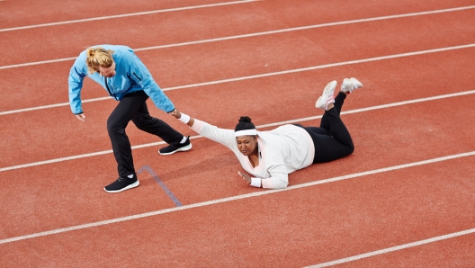 Persistent trainer pulling reluctant plus-size woman along racetrack towards finish line