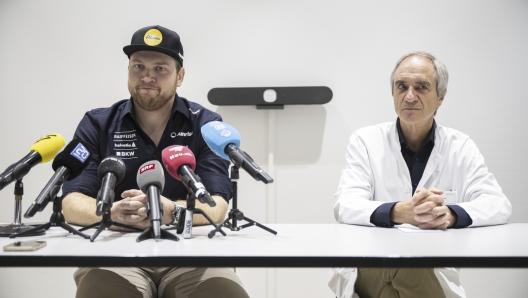 Swiss ski racer Niels Hintermann, left, talks about his health to communicate that he will skip the upcoming 2024/25 competition season, as he sits next to Walter O. Frey, responsible doctor for alpine skiing, at a media conference at the Hirslanden Clinic in Zurich, Switzerland, Wednesday, Oct. 9, 2024. (Ennio Leanza/Keystone via AP)