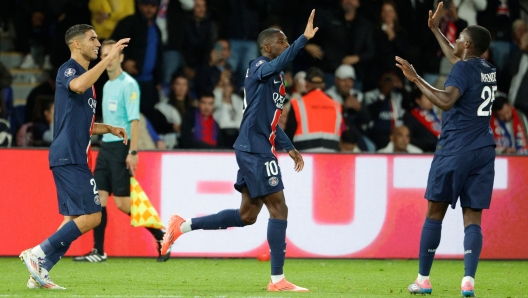 Paris Saint-Germain's French forward #10 Ousmane Dembele (C) celebrates with teammates after scoring PSG's first goal with Paris Saint-Germain's Slovak defender #37 Milan Skriniar (R) during the French L1 football match between Paris Saint-Germain (PSG) and Stade Brestois 29 (Brest) at The Parc des Princes Stadium, in Paris, on September 14, 2024. (Photo by GEOFFROY VAN DER HASSELT / AFP)