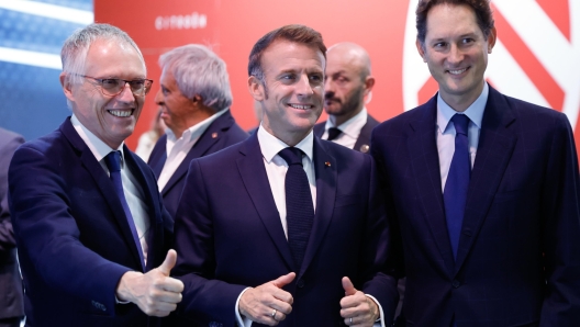 epa11658659 French President Emmanuel Macron (C) poses alongside Stellantis CEO Carlos Tavares (L) and Stellantis chairperson John Elkann (R) during his visit to the Stellantis stand at the Paris Motor Show in Paris Expo Porte de Versailles in Paris, France, 14 October 2024. The 90th edition of the biennial Paris Motor Show runs from 14 to 20 October 2024.  EPA/LUDOVIC MARIN / POOL  MAXPPP OUT