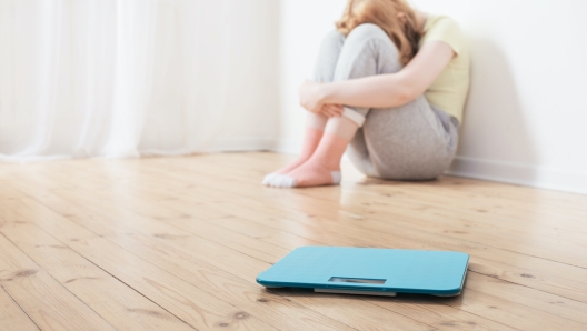 sad teenager girl with scale on wooden floor