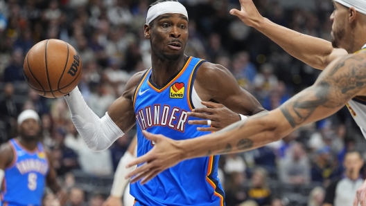 Oklahoma City Thunder guard Shai Gilgeous-Alexander, left, looks to pass the ball as Denver Nuggets forward Michael Porter Jr. defends in the second half of an NBA basketball game Thursday, Oct. 24, 2024, in Denver. (AP Photo/David Zalubowski)