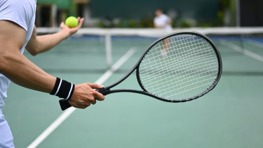 Tennis player serving tennis ball during a match on open court. Sport, training and active life concept.