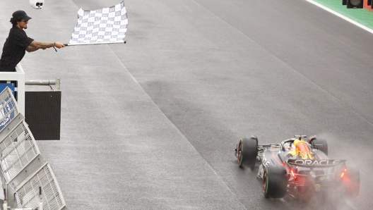 Brazilian surfer Gabriel Medina waves the chequered flag to Red Bull Racing's Dutch driver Max Verstappen after winning the Formula One Sao Paulo Grand Prix, at the Jose Carlos Pace racetrack, aka Interlagos, in Sao Paulo, Brazil, on November 3, 2024. (Photo by Sebastiao Moreira / POOL / AFP)