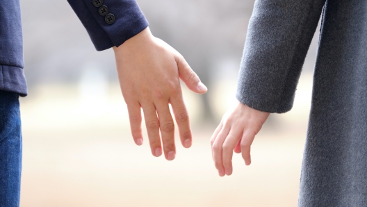 A Japanese man and woman holding hands in a park in winter