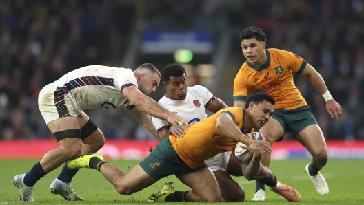 Australia's Len Ikitau, front, is tackled by England's Ben Earl, left, and teammate Immanuel Feyi-Waboso during the Autumn Nations series rugby union match between England and Australia, at Twickenham stadium, London Saturday, Nov. 9, 2024. (AP Photo/Ian Walton)