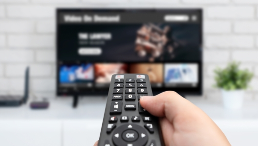 Man watching TV, remote control in hand. VOD service on TV