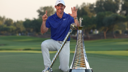 DUBAI, UNITED ARAB EMIRATES - NOVEMBER 17: Rory McIlroy of Northern Ireland poses with the DP World Tour Championship trophy and the Race to Dubai trophy on the 18th green whilst gesturing 'six' for his sixth Race to Dubai title, on day four of the DP World Tour Championship 2024 at Jumeirah Golf Estates on November 17, 2024 in Dubai, United Arab Emirates. (Photo by Richard Heathcote/Getty Images)