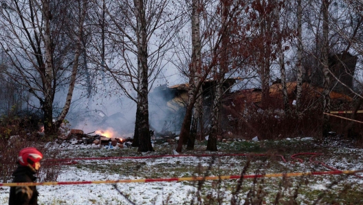 A Lithuanian rescuer walks past the wreckage of a cargo plane following its crash near the Vilnius International Airport in Vilnius on November 25, 2024. (Photo by Petras MALUKAS / AFP)