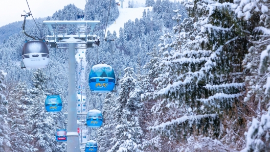 Bansko, Bulgaria - January 21, 2024: Winter ski resort panorama with blue gondola lift cabins, snow forest pine trees, mountain peaks view