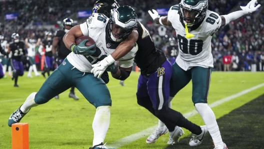 Philadelphia Eagles running back Saquon Barkley, left, is hit by Baltimore Ravens cornerback Marlon Humphrey, center, as Eagles wide receiver Parris Campbell (80) looks on during a touchdown run by Barkley in the second half of an NFL football game, Sunday, Dec. 1, 2024, in Baltimore. (AP Photo/Stephanie Scarbrough)