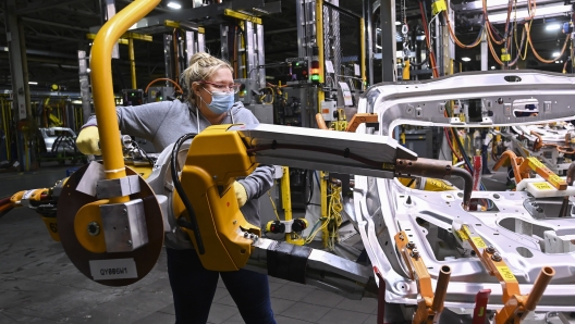 FILE - GM workers use human assistance automation to weld vehicle doors at the General Motors assembly plant during the COVID-19 pandemic in Oshawa, Ontario, March 19, 2021. (Nathan Denette/The Canadian Press via AP, File)