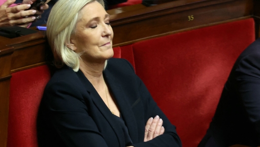 TOPSHOT - President of Rassemblement National parliamentary group Marine Le Pen reacts during the debate prior to the no-confidence votes on Prime Minister Michel Barnier's administration at the National Assembly in Paris on December 4, 2024. The French National Assembly debates two motions brought by the French left-wing Nouveau Front Populaire (New Popular Front) NFP coalition and the French far-right Rassemblement National (National Rally) RN party in a standoff over 2025's austerity budget, which saw French Prime Minister force through a social security financing bill without a vote (article 49.3) on December 2, 2024. (Photo by Alain JOCARD / AFP)