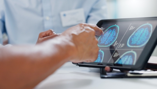 Doctor, hands and tablet with brain scan for patient, consultation or examination results at hospital. Closeup of person, medical employee or nurse pointing to technology for MRI at neurology clinic