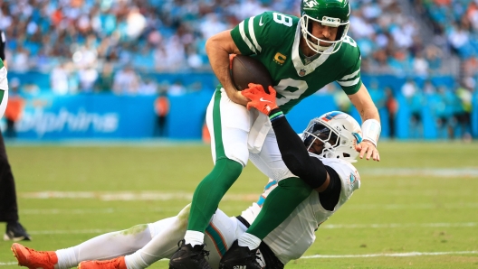 MIAMI GARDENS, FLORIDA - DECEMBER 08: Aaron Rodgers #8 of the New York Jets is tackled by Jordyn Brooks #20 of the Miami Dolphins in the third quarter at Hard Rock Stadium on December 08, 2024 in Miami Gardens, Florida.   Megan Briggs/Getty Images/AFP (Photo by Megan Briggs / GETTY IMAGES NORTH AMERICA / Getty Images via AFP)