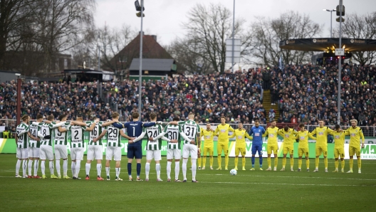 Players observe as minute of silence to honor the victims of the Christmas Market attack in Magdeburg, ahead of the German Bundesliga 2, soccer match between Preußen Muenster and SSV Ulm 1846, in Muenster, Germany, Saturday, Dec. 21, 2024. (Bernd Thissen/dpa via AP)