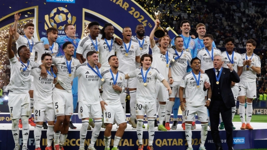 TOPSHOT - Real Madrid's Italian coach Carlo Ancelotti and his players celebrate on the podium after winning the 2024 FIFA Intercontinental Cup final football match against Mexico's Pachuca at the Lusail Stadium in Doha on December 18, 2024. (Photo by KARIM JAAFAR / AFP)