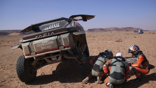 Driver Nasser Al-Attiya and co-driver Edouard Boulanger are helped by driver Cristina Gutierrez and co-driver Pablo Moreno during the fourth stage of the Dakar Rally between Al Henakiyah and Alula, Saudi Arabia, Wednesday, Jan. 8, 2025. (AP Photo/Christophe Ena)