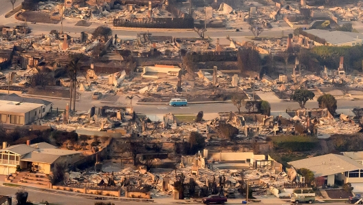 TOPSHOT - In this aerial view taken from a helicopter, burned homes are seen from above during the Palisades fire near the Pacific Palisades neighborhood of Los Angeles, California on January 9, 2025. Massive wildfires that engulfed whole neighborhoods and displaced thousands in Los Angeles remained totally uncontained January 9, 2025, authorities said, as US National Guard soldiers readied to hit the streets to help quell disorder. Swaths of the United States' second-largest city lay in ruins, with smoke blanketing the sky and an acrid smell pervading almost every building. (Photo by JOSH EDELSON / AFP)