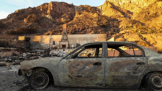 Scorched cars and burned-out homes destroyed by the Palisades Fire are seen along the Pacific Coast Highway in Malibu, California on January 10, 2025. Massive wildfires that engulfed whole neighborhoods and displaced thousands in Los Angeles have killed at least 10 people, authorities said, as California's National Guard soldiers readied to hit the streets to help quell disorder. News of the growing toll, announced late Thursday January 9 by the Los Angeles County Medical Examiner, came as swaths of the United States' second-largest city lay in ruins. (Photo by VALERIE MACON / AFP)