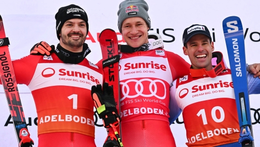 (From L) Second-placed Switzerland's Loic Meillard, winner Switzerland's Marco Odermatt and third-placed Italy's Luca De aliprandini celebrate on the podium after competing in the Men's Giant Slalom race as part of the FIS Alpine ski World Cup 2024-2025, in Adelboden on January 12, 2025. (Photo by FABRICE COFFRINI / AFP)